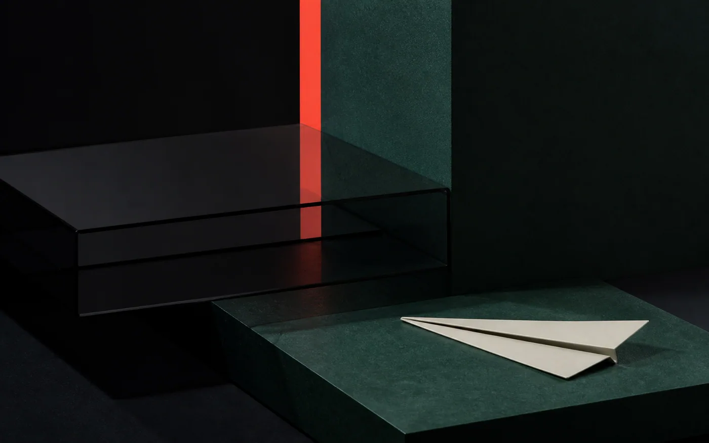 Abstract architectural material study with deep-green planes, a coral light band, dark metal rails, and a folded cream form.